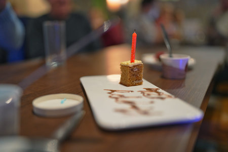 Celebration cake with a candle set on a table during a gathering at a casual restaurant in the...