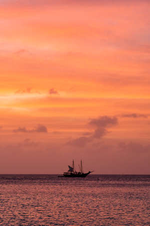 A boat silhouette against a Caribbean sunsetの写真素材