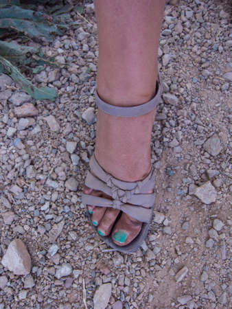 Feet dirty with brown shoes on floor with rocksの写真素材