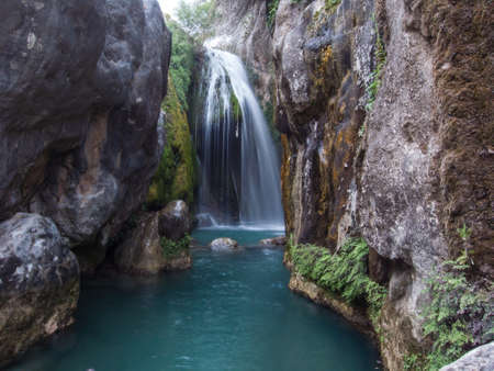 small waterfall with movement flowing into a smerald riverの写真素材