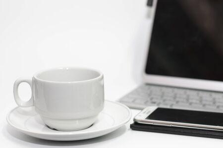 Coffee cup on white desk and laptop for background,drink between working,selective focus.の写真素材