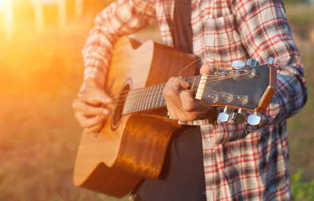 Hand of man playing guitar in outdoor,soft focus.