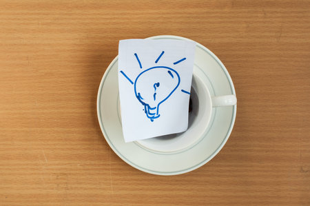 Light bulb idea paper in coffee cup on wood background,concept,soft focus.