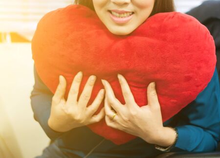 Heart red pillow shape in hand female,focus at pillow.の写真素材