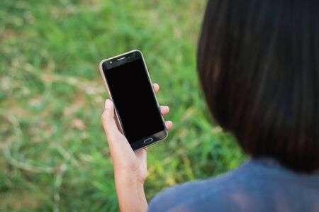 Young woman read and playing smartphone in park,selective focus.の写真素材