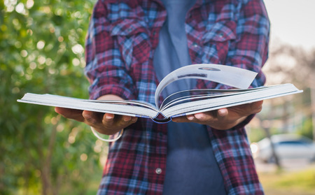 Young woman reading book in park,selective focus.の写真素材