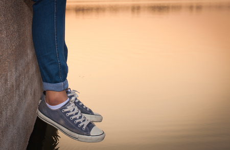Woman legs hanging at lake in park for relax.の写真素材