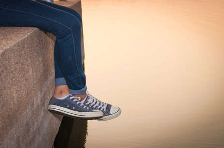 Woman legs hanging at lake in park for relax.の写真素材