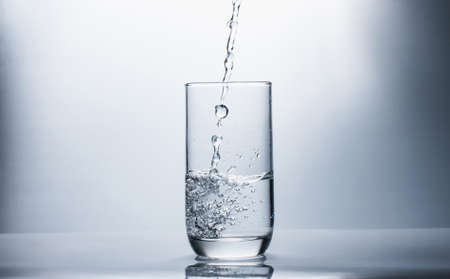 Drink water falling in glass,selective focus.の写真素材