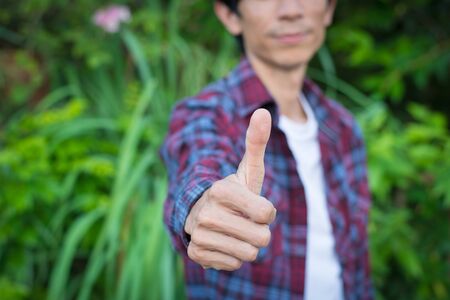Man showing thumb up in garden,selective focus.の写真素材