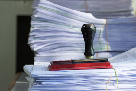 Rubber stamp on pile of document in office room,selective focus.の写真素材
