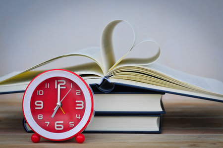 Old book and clock on wooden table,soft focus.