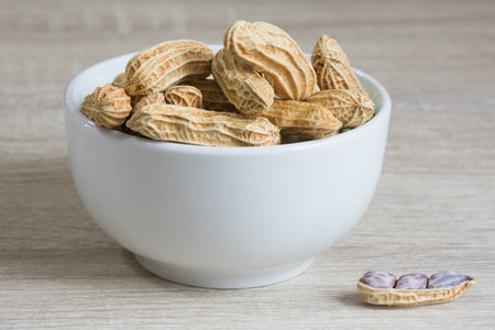 Group of peanut in white cup on wooden table background,copy space.