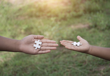 White jigsaw puzzle in child hand,team concept,soft focus.の写真素材