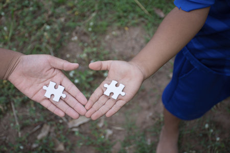 White jigsaw puzzle in child hand,team concept,soft focus.の写真素材