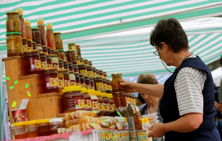 Sofia, Bulgaria - September 15, 2014: A seller is arranging his jars of honey some of which mixed with nuts and fruits. He is participating in a annual Honey festival in Sofia, where honey producers show and sell their productions from all over the countrのeditorial素材
