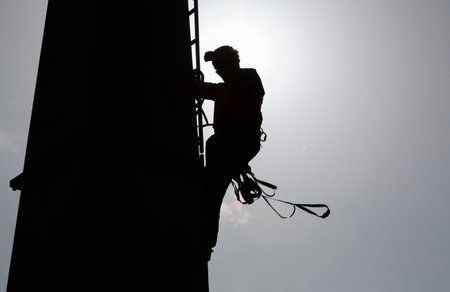 Silhouetee of a person climbing a cabin lift pillar.の写真素材