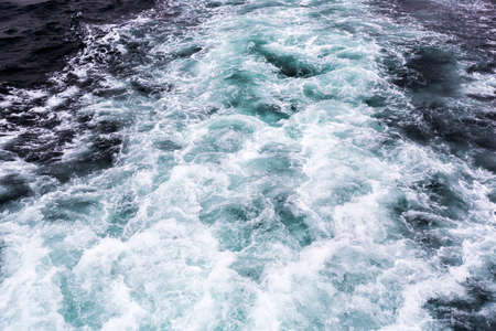 Wate waves are being formed behind a boat.の写真素材