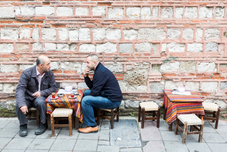 Istanbul, Turkey - November 15, 2014: Two Turkish men are drinking tea outside of a cafe at a market street in Istanbul.のeditorial素材