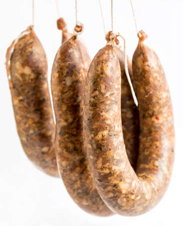 Three raw flat sausages isolated on a white background. Traditional Bulgarian meat appetizer.の写真素材
