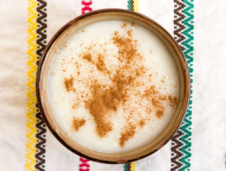 Milk and rice with cinnamon from above on an embroidered cloth.の写真素材