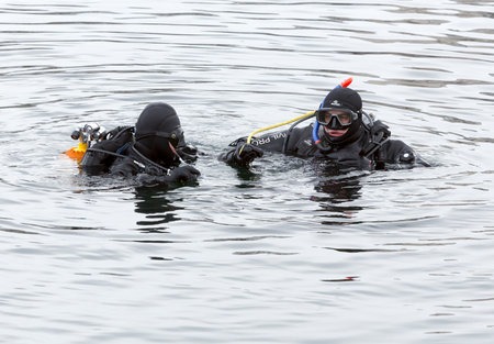 Sofia, Bulgaria - January 6, 2015: Two divers are swimming into the frozen lake waters before Bulgarian men jump for a wooden cross at Epiphany day celebration in Sofia.のeditorial素材