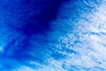 Skyscape with wispy clouds against the colorful blue skyの写真素材