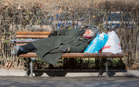 Sofia, Bulgaria - February 26, 2015: Homeless woman is sleeping on a bench in the park next to the parliament in Sofia, Bulgaria. Years after joining the EU Bulgaria is still the poorest country in the union.のeditorial素材