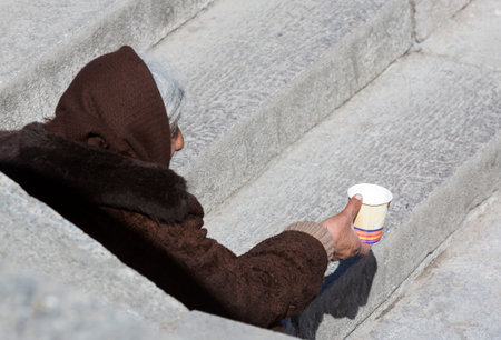 A homeless female begger is begging at the subway underpass stairs in the center of Sofia.