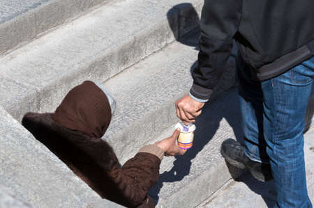 A man is giving money to a homeless female begger who is begging at the subway underpass stairs in the center of Sofia.の写真素材