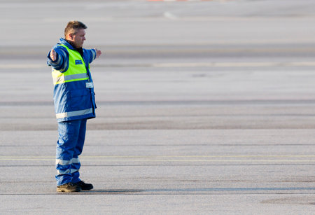 Sofia, Bulgaria - April 11, 2015: An airport worker is navigating the movement of an airplane on the airport runway after landing.のeditorial素材