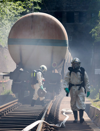 A team working with toxic acids and chemicals is approaching a chemical cargo train crash near...