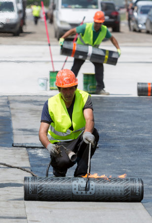 Sofia, Bulgaria - May 21, 2015: Construction workers are waterproofing a bridge surface floor at a...