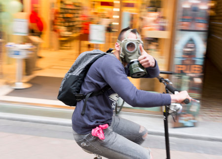 Budapest, Hungary - April 30, 2015: An young Hungarian boy with gas mask is driving a two wheel scooter in a central street in Budapest.のeditorial素材