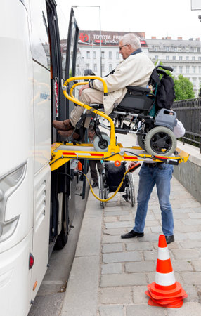 Vienna, Austria - May 1, 2015: A bus driver helps physically disabled person in a wheelchair to board in the bus.のeditorial素材