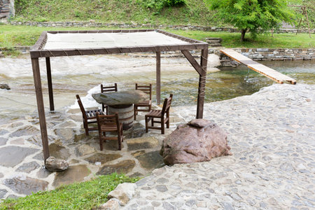Authentic Bulgarian restaurant with wooden chairs and stone tables near the river.の写真素材