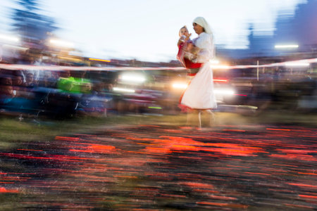 Rozhen, Bulgaria - July 18, 2015: A nestinar woman with a child is walking on fire during a nestinarstvo show. The fire ritual involves a barefoot dance on smouldering embers performed by nestinari.のeditorial素材