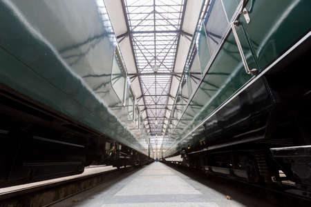 Old authentic green passenger trains in a depot for renovation before being used for tourist trips across Europe. Details of the train's transmission.の写真素材