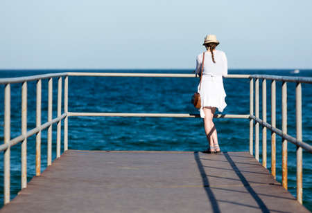 An young woman is watching the waters of Black sea from a pier in Sozopol, Bulgaria.の写真素材