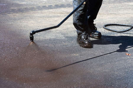 Worker is spraying the black hot asphalt at a road construction.の写真素材
