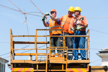 Sofia, Bulgaria - August 18, 2015: Three elecrticity construction workers on a platform are...