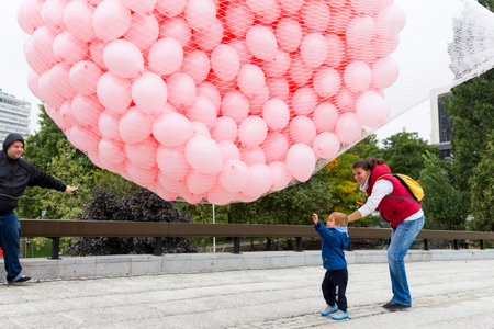 Sofia, Bulgaria - October 19, 2015: Young boy is enjoying more than a thousand pink balloons prepared to be released in memory of every woman died from breast cancer last year.のeditorial素材