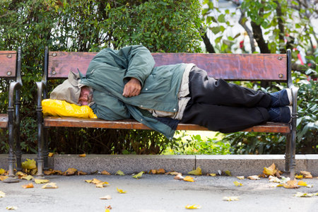 Sofia, Bulgaria - October 28, 2015: Homeless person is sleeping on a bench in a cold autumn day in a park in European union's poorest country Bulgaria.のeditorial素材