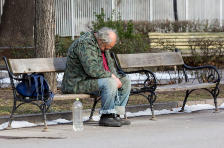 A homeless man is sitting and sleeping on a bench in a park in Bulgaria's capital Sofia. Years after joining the EU the country is still struggling with great poverty among its citizens.のeditorial素材