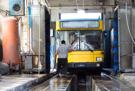The driver of the trolley car is washing the vehicle in the tram depot.のeditorial素材