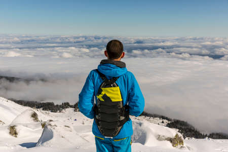 Freestyle skier is looking from the top of a peak of Vitosha mountain covored in clouds. He is participating in an freestyle competition of skiers and snowboarders.の写真素材