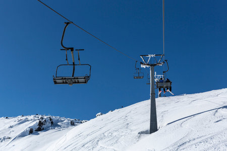 A ski lift is transporting skiers and snowboarders into the Vitosha mountain top's ski slopes...