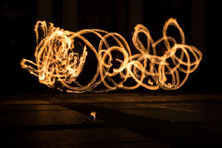 Performers are spinning torches while performing a fire show at night celebrating the international Earth hour event in Sofia, Bulgaria. Long exposure.の写真素材
