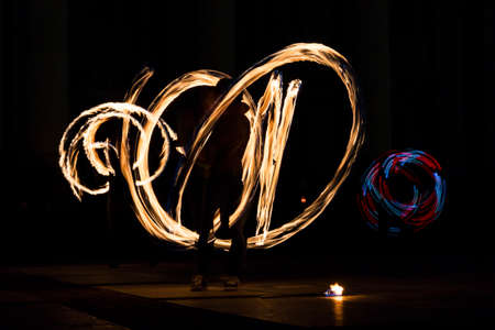 Long exposure image of an art performer at a fire show in the dark.の写真素材