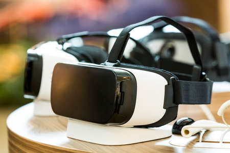 Virtual reality (VR) headsets (glasses) on a table. VR is immersive multimedia or computer-simulated reality - a computer technology that replicates an environment and simulates a user's physical presence and environment to allow for user interactionの写真素材
